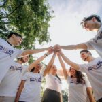 Un groupe de jeunes adultes en chemises blanches partageant un moment de joie en équipe à l'extérieur.