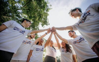 Un groupe de jeunes adultes en chemises blanches partageant un moment de joie en équipe à l'extérieur.