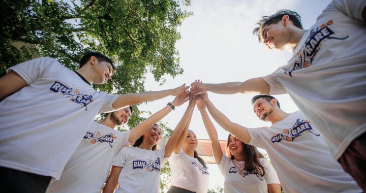 Un groupe de jeunes adultes en chemises blanches partageant un moment de joie en équipe à l'extérieur.