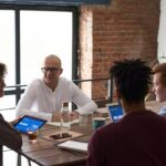 Équipe diversifiée collaborant dans un environnement de bureau moderne avec des ordinateurs portables et des notes sur la table.