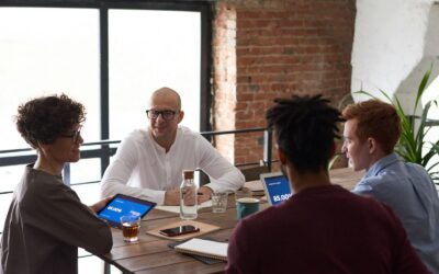 Équipe diversifiée collaborant dans un environnement de bureau moderne avec des ordinateurs portables et des notes sur la table.