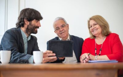 Groupe de trois personnes discutant autour d'une table avec une tablette et des tasses