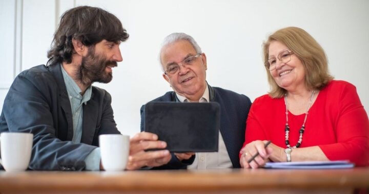 Groupe de trois personnes discutant autour d'une table avec une tablette et des tasses