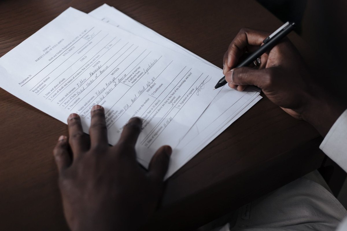 Mains noires écrivant sur un papier avec un stylo sur une table Mains noires écrivant sur un papier avec un stylo sur une table