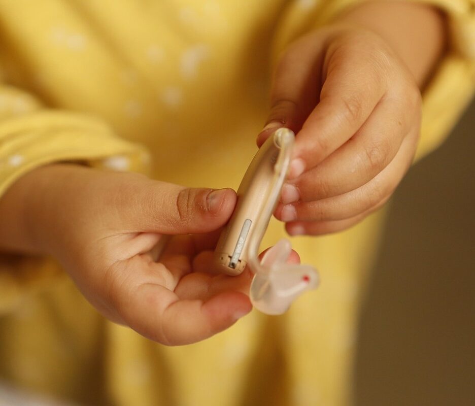 Un enfant tient un appareil auditif et son petit embout en main