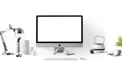 Bureau avec écran Apple, clavier, souris, lampe, tasse, théière et objets divers