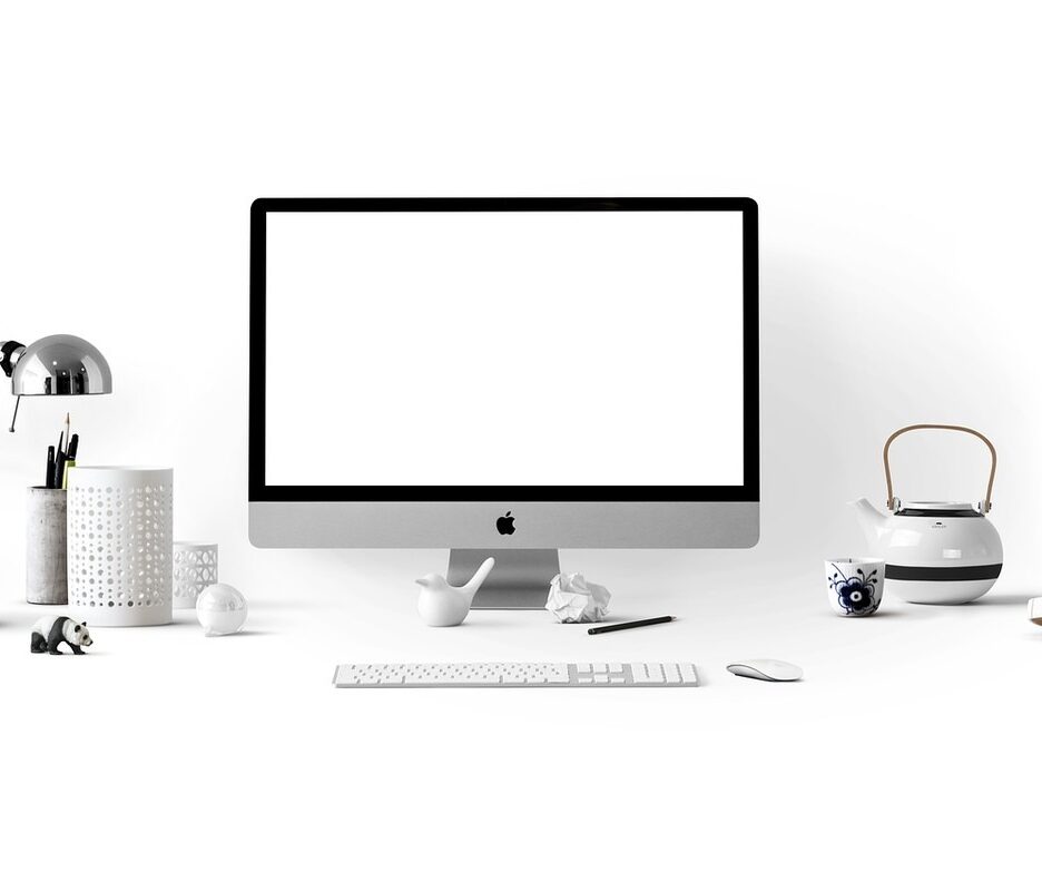 Bureau avec écran Apple, clavier, souris, lampe, tasse, théière et objets divers