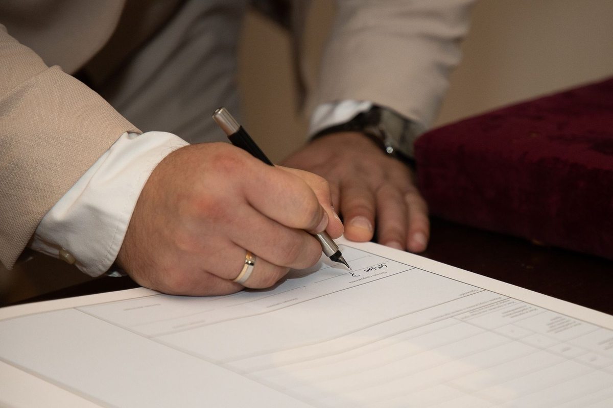 Mains écrivant sur un document avec un stylo, montre et anneau visibles