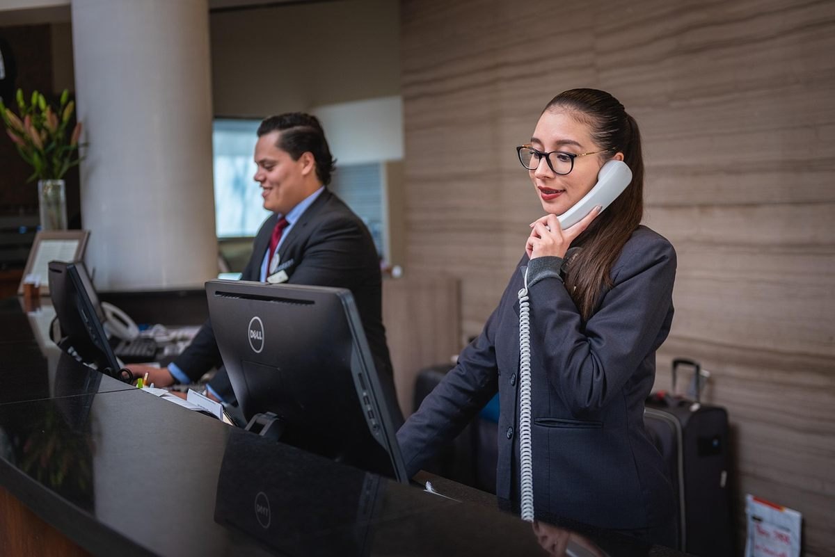 Réceptionniste en conversation téléphonique dans un hall d'hôtel moderne